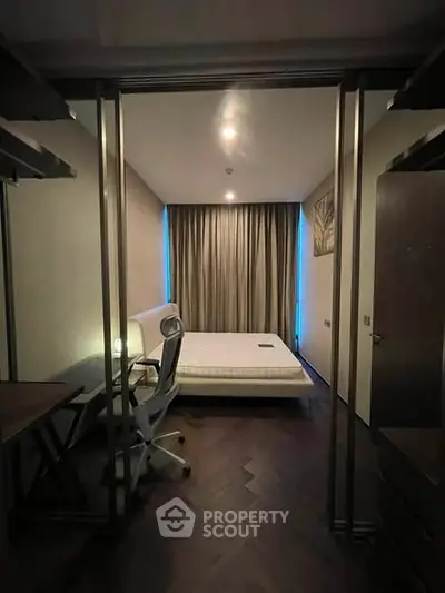 Modern bedroom with sleek design and workspace, featuring a comfortable bed and stylish chair.