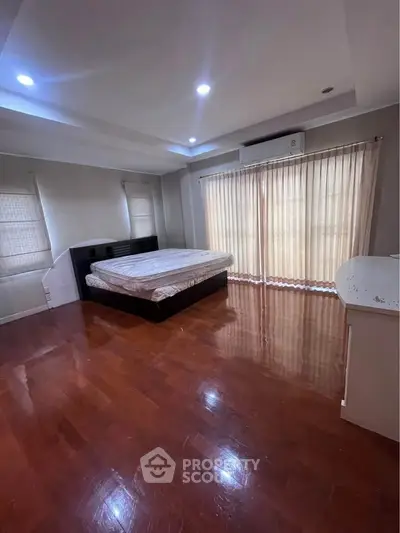 Spacious bedroom with wooden flooring and natural light