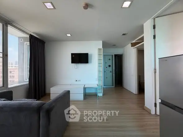 Modern living room with sleek furniture and large windows offering city views.