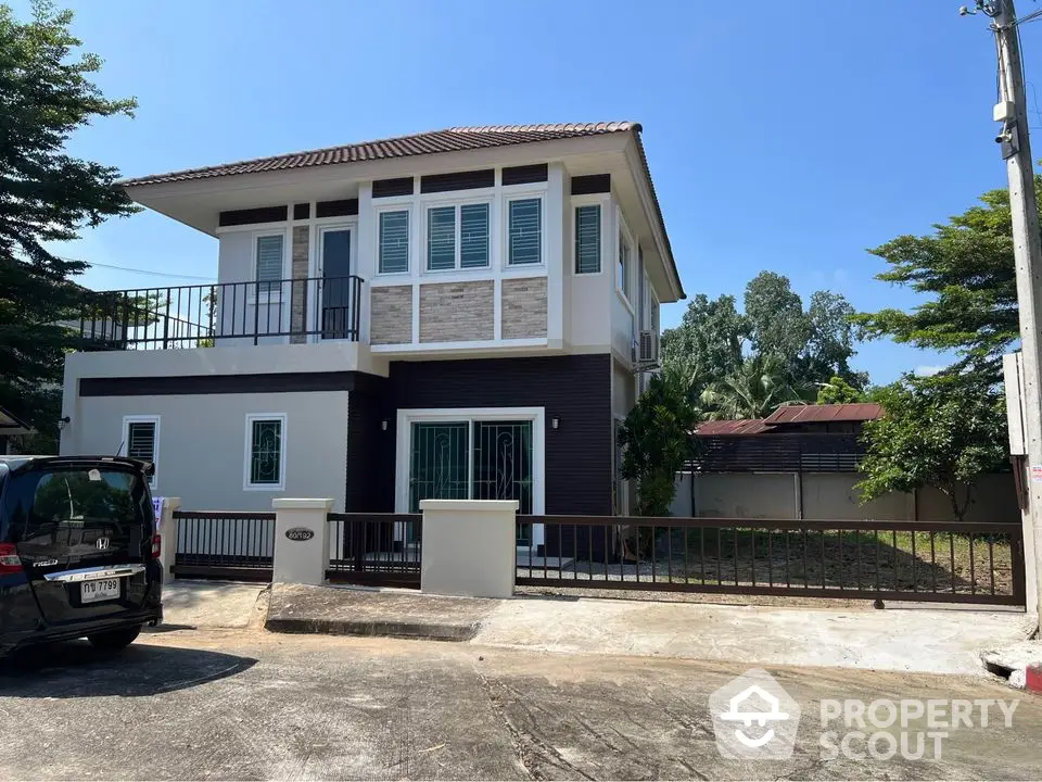 Modern two-story house with balcony and spacious driveway in serene neighborhood.