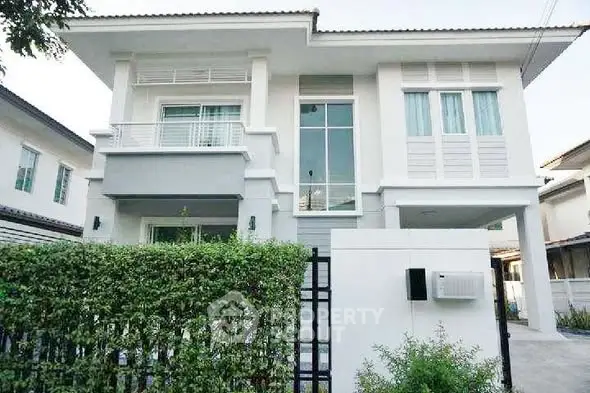 Modern two-story house with large windows and lush greenery in a suburban neighborhood.