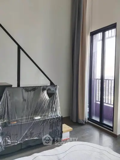 Modern living room with large windows and staircase, featuring sleek design and natural light.
