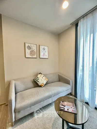 Cozy living room with modern sofa, stylish decor, and natural light from large window.