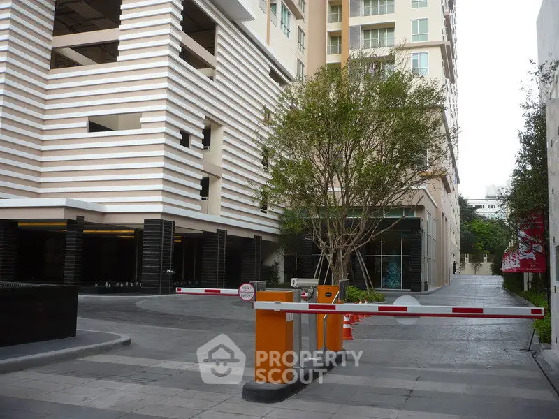 Modern building entrance with security barrier and lush greenery