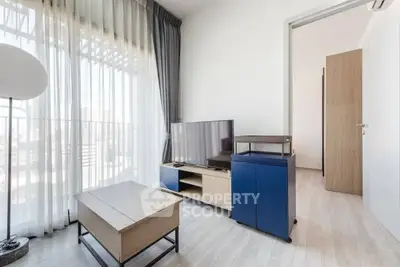Modern living room with sleek furniture and natural light, featuring a TV and stylish decor.