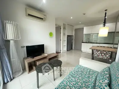 Modern living room with open kitchen, featuring stylish furniture and bright lighting.