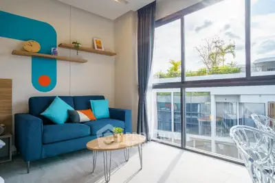 Modern living room with blue sofa and large window offering natural light and garden view.