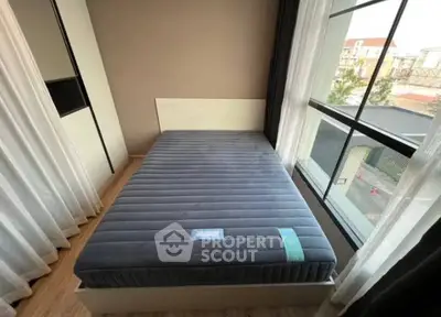 Modern bedroom with large window and stylish bed, offering natural light and a cozy atmosphere.