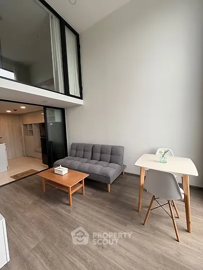 Modern loft-style living room with high ceiling and minimalist furniture