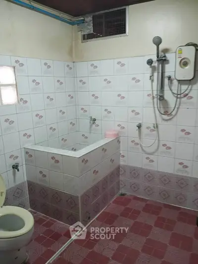 Cozy bathroom with tiled walls and floor, featuring a shower and toilet, ideal for compact living spaces.