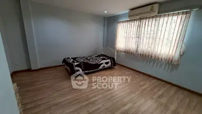 Spacious bedroom with wooden flooring and natural light