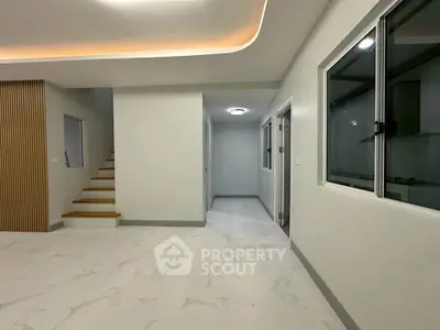 Modern interior with sleek staircase and open layout, featuring elegant lighting and large windows.