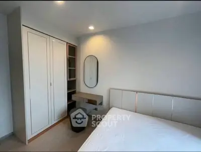 Modern bedroom with sleek wardrobe and stylish mirror in a minimalist design.
