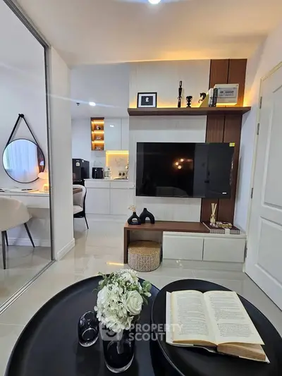 Modern living room with sleek decor and open layout, featuring a wall-mounted TV and stylish furniture.