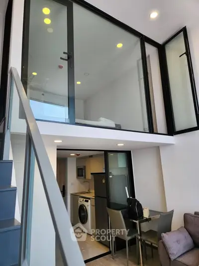 Modern duplex apartment with glass-walled mezzanine and sleek kitchen
