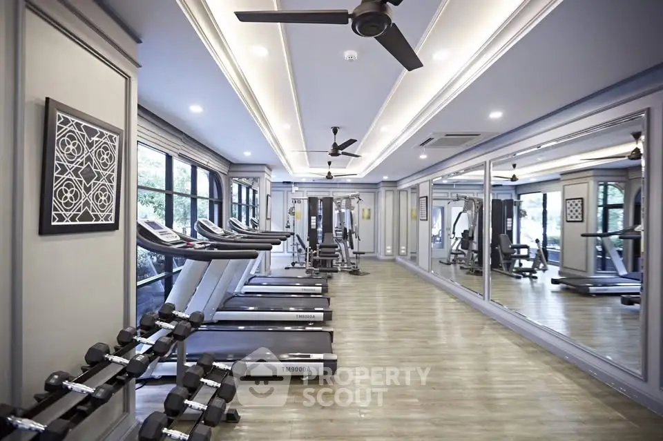 Luxurious gym with modern equipment and mirrored walls in upscale residential building.