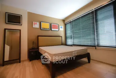 Spacious bedroom with modern decor and large windows with blinds