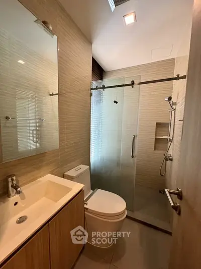 Modern bathroom with glass shower and sleek fixtures in contemporary home.