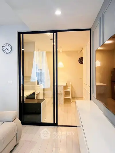 Modern living room with glass partition and cozy dining area, featuring elegant lighting and stylish decor.