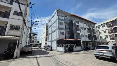 Modern apartment building exterior with parking area and clear blue sky.