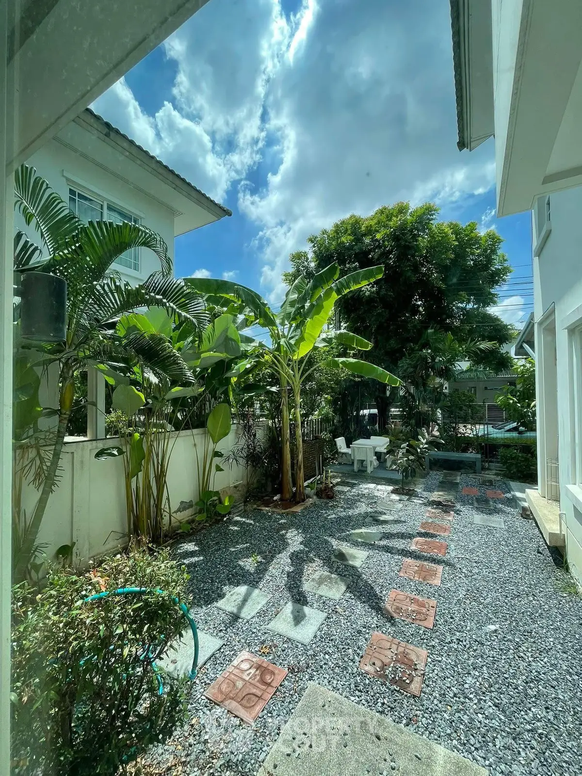 Charming garden view with lush greenery and stone pathway in a serene residential area.