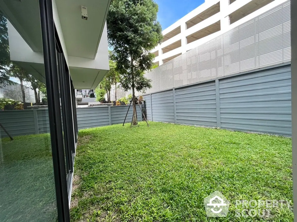 Lush private garden space in a modern residential complex, perfect for outdoor relaxation and entertainment, surrounded by contemporary fencing.