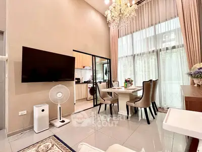 Luxurious high-ceiling living room with elegant chandelier and modern kitchen access