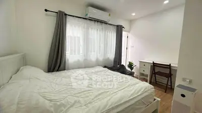 Cozy bedroom with natural light, featuring a study desk and air conditioning.