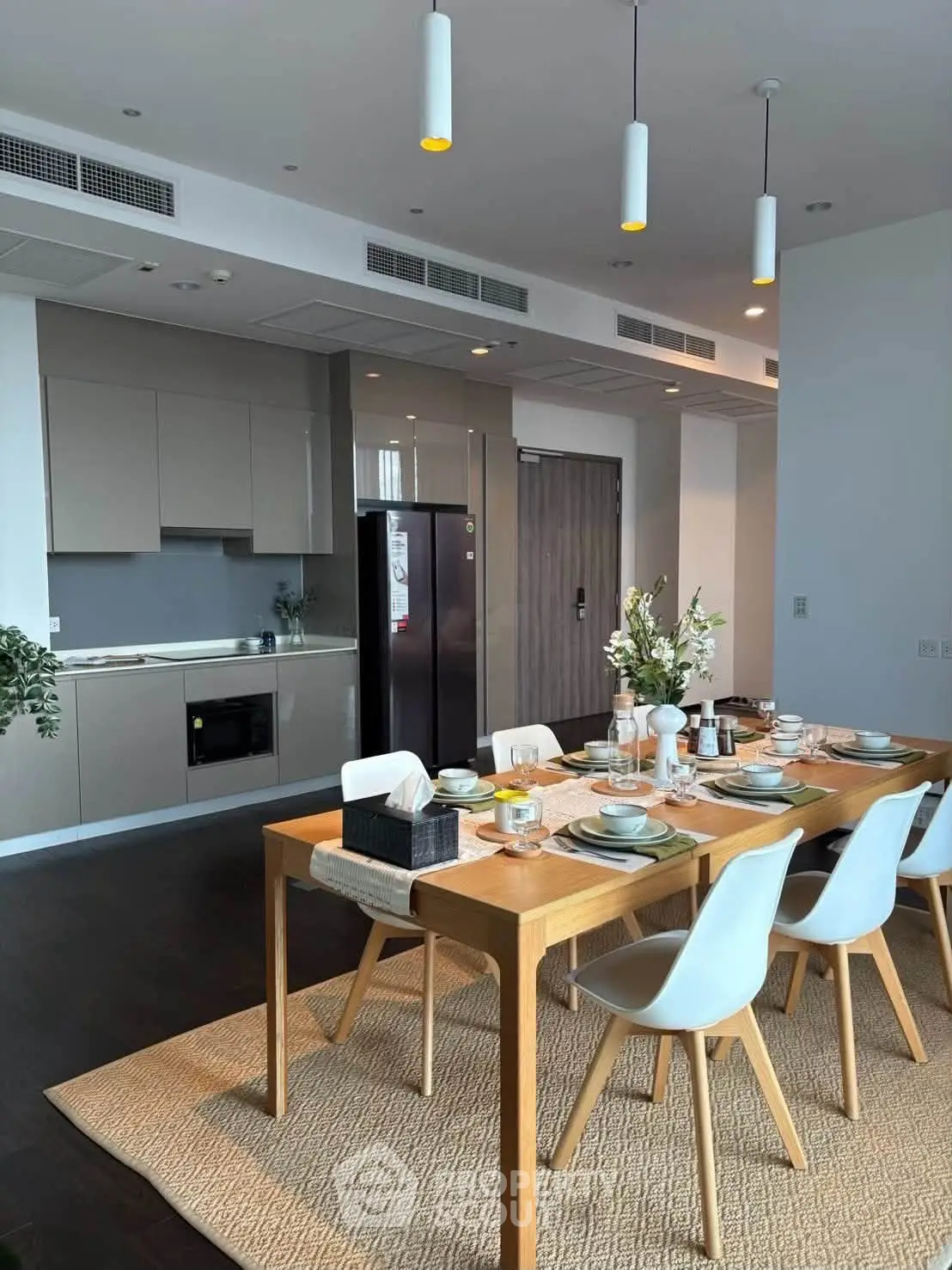 Modern dining area with elegant table setting and sleek kitchen design in open layout apartment.