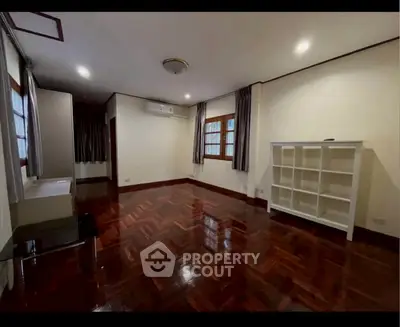 Spacious living room with polished wooden floors and built-in shelves, ideal for modern living.
