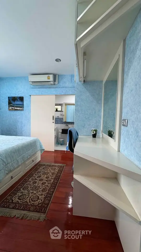 Charming bedroom with blue accents and built-in vanity, featuring a cozy atmosphere and wooden flooring.