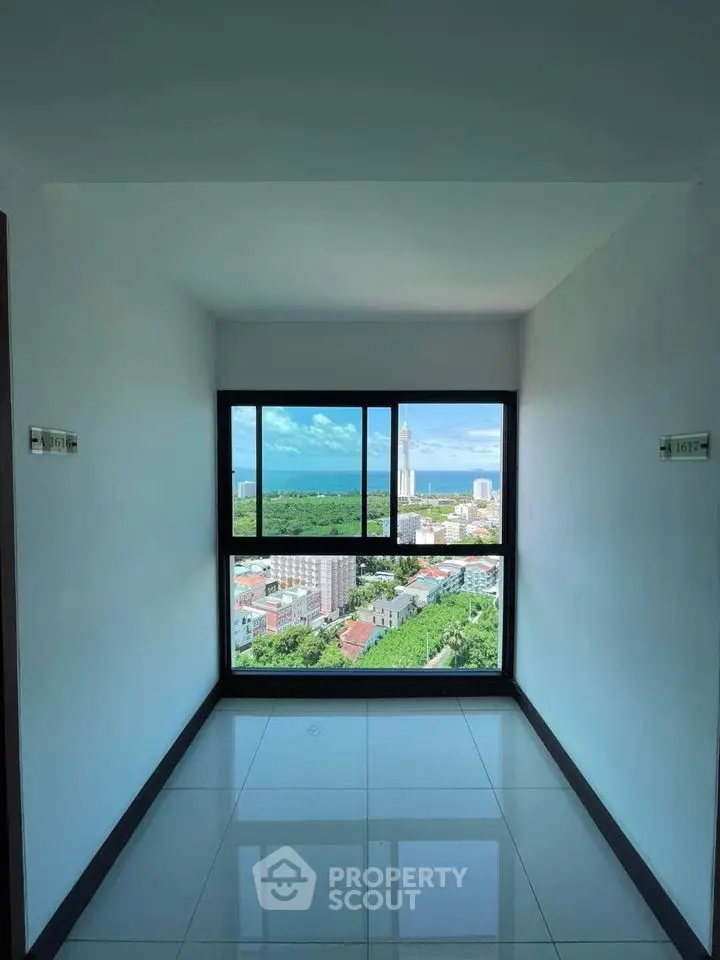 Stunning high-rise view of cityscape and ocean from modern apartment window.