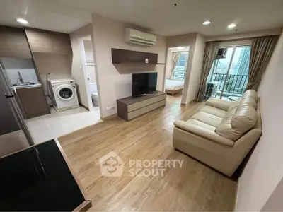 Modern apartment interior with open living room, kitchen, and balcony view.