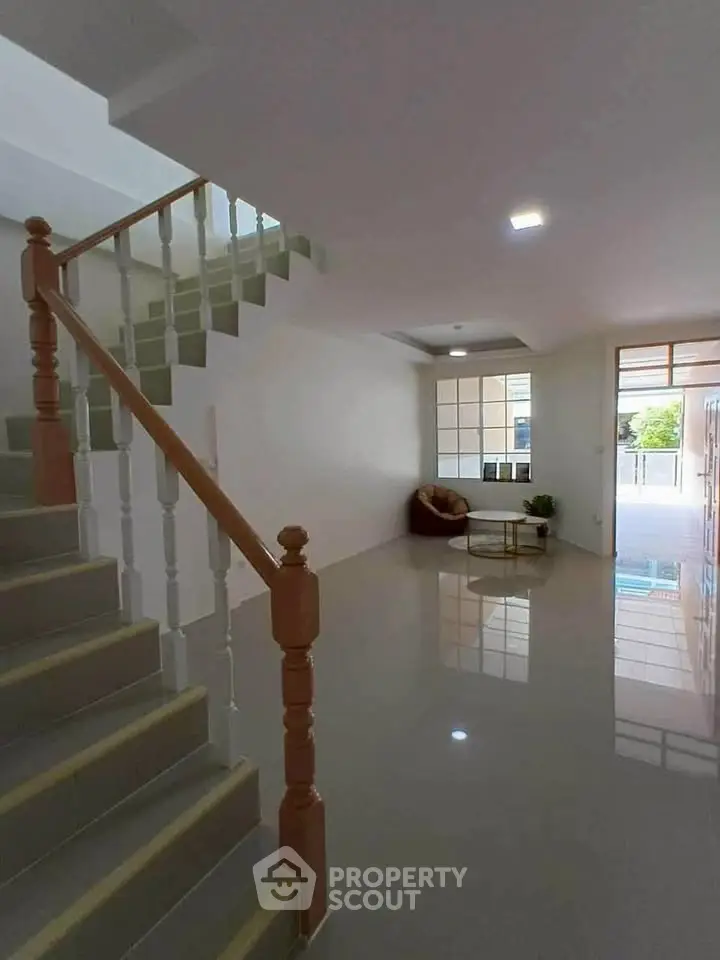 Spacious modern living room with staircase and large windows, perfect for natural light.