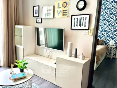 Stylish modern living room with TV, art decor, and glimpse of cozy bedroom.