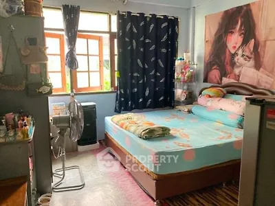 Cozy bedroom with large window, vibrant decor, and ample natural light.