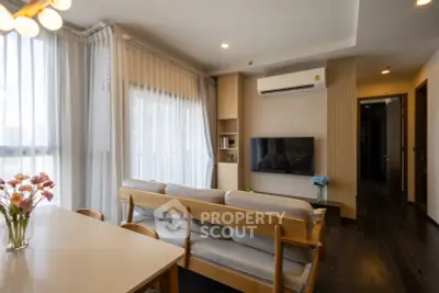 Modern living room with stylish furniture and natural light, featuring a wall-mounted TV and air conditioning.