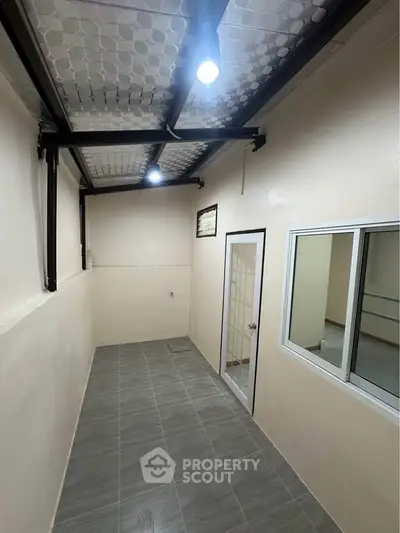 Spacious enclosed balcony with tiled flooring and modern lighting, perfect for relaxation or utility use.