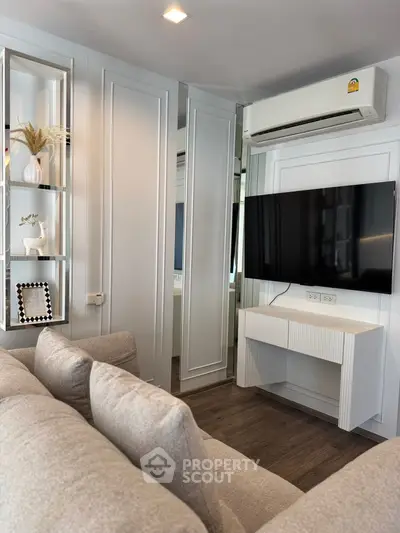 Modern living room with sleek design, featuring a wall-mounted TV, air conditioning, and stylish decor.