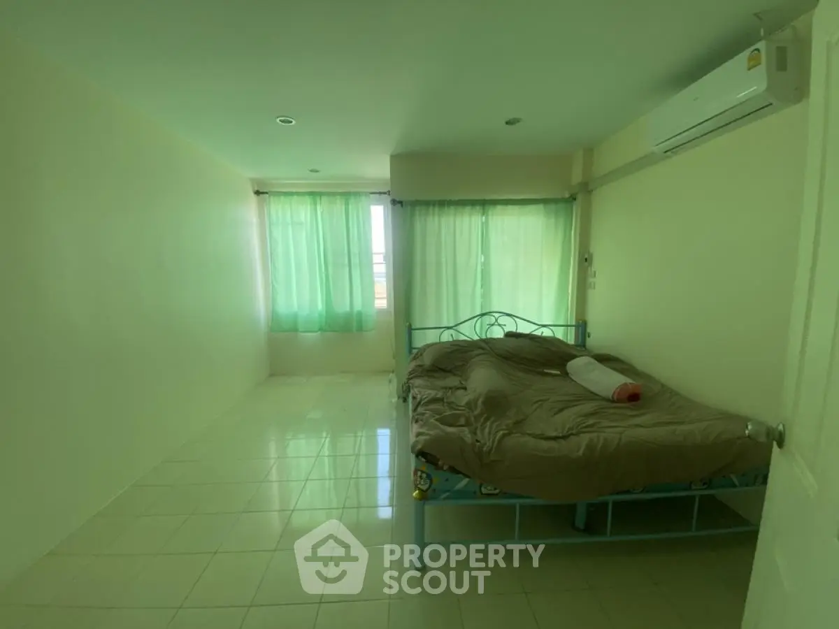 Spacious bedroom with natural light and air conditioning in modern apartment.