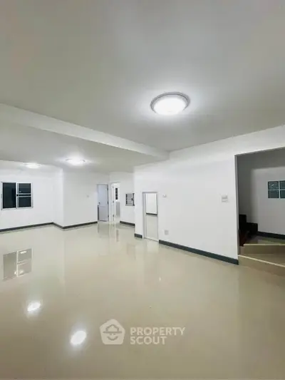Spacious open-plan living room with modern lighting and glossy tiled floors.