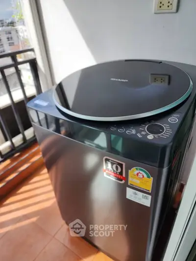 Modern washing machine on a sunny balcony with city view, perfect for urban living convenience.