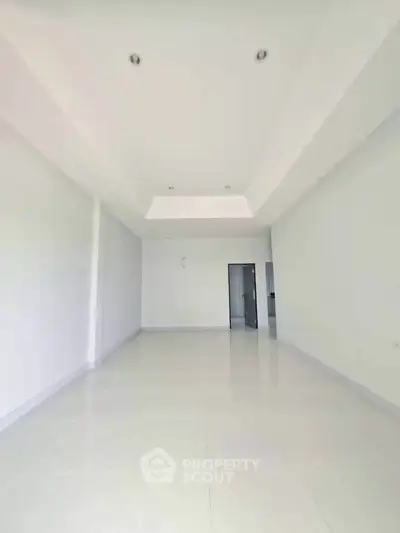 Spacious empty room with white walls and recessed lighting, ideal for customization.