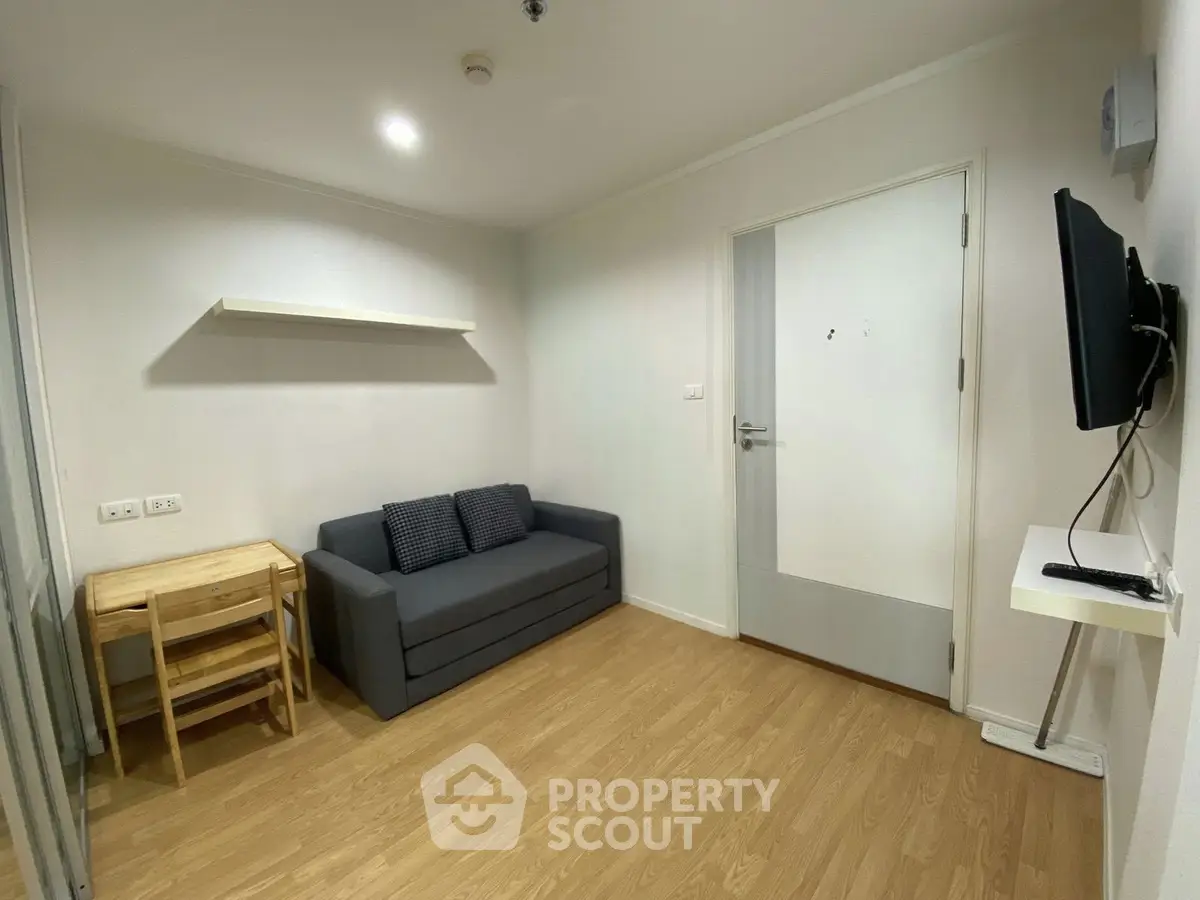 Cozy living room with modern sofa and wall-mounted TV in a compact apartment.