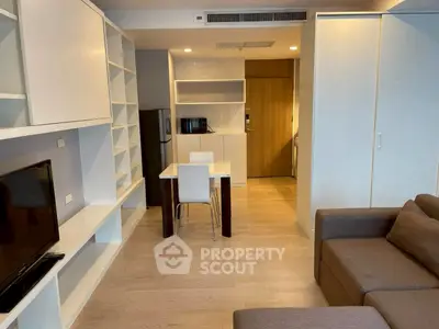 Modern living room with open kitchen, sleek furniture, and ample storage in a stylish apartment.