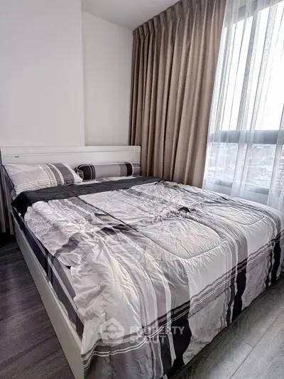 Modern bedroom with stylish bedding and large window offering natural light.