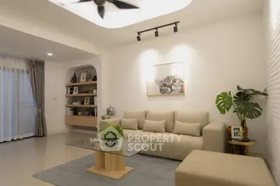 Modern living room with beige sofa, glass coffee table, and cat artwork on wall.
