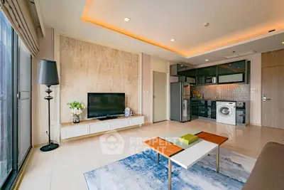 Modern living room with open kitchen, featuring sleek appliances and stylish decor.