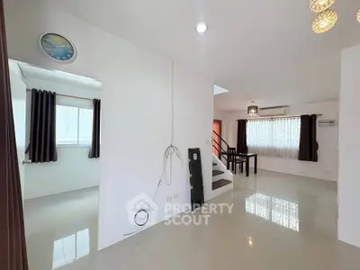Spacious modern interior with glossy floors and ample natural light, featuring a staircase and dining area.