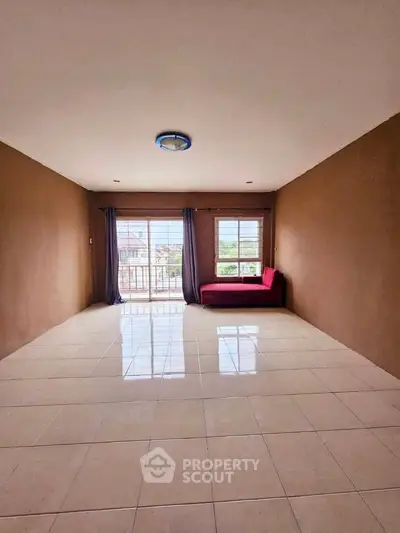 Spacious living room with large windows and a cozy red sofa, perfect for relaxation.